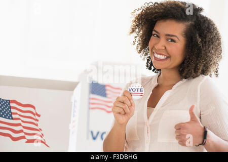 Giovane donna azienda badge di voto e sorridente Foto Stock