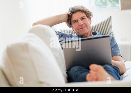 Uomo maturo utilizzando computer portatile sul divano Foto Stock