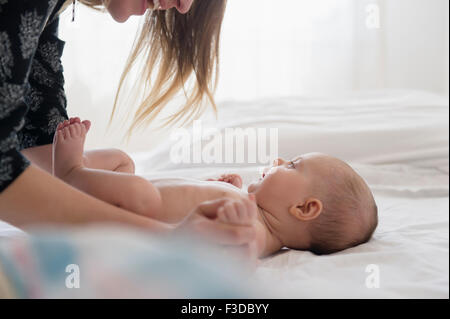 La madre gioca con baby girl (2-5 mesi) sul letto Foto Stock