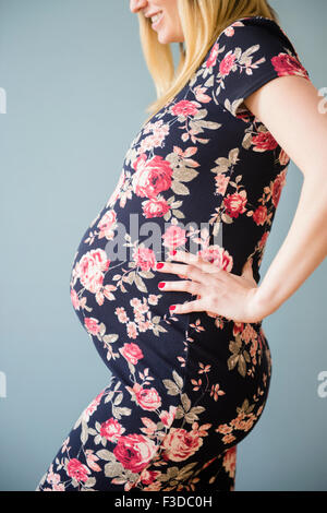 Studio shot della donna incinta in abito floreale Foto Stock