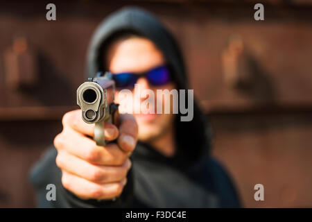 Uomo con pistola rivolta verso la telecamera Foto Stock