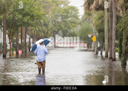 Charleston, Carolina del Sud, Stati Uniti d'America. 05 ott 2015. Un residente passeggiate attraverso acque alluvionali a casa sua nel quartiere storico dopo il record di tempeste di rottura oggetto di dumping più di due piedi di pioggia sul lowcountry Ottobre 5, 2015 a Charleston, Carolina del Sud. Foto Stock