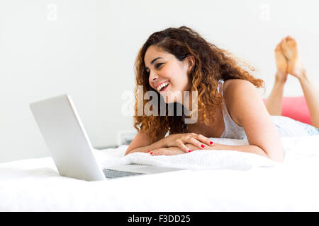 Donna che utilizza computer portatile a letto Foto Stock