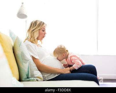 La ragazza (2-3) kissing ventre della madre Foto Stock