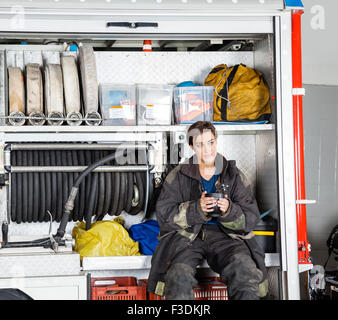 Riflessivo firewoman holding tazza da caffè nel carrello Foto Stock