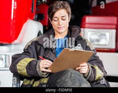 Firewoman iscritto sulla clipboard contro camion Foto Stock