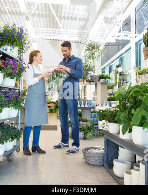 Fioraio assistere il cliente nell'acquisto di bouquet Foto Stock