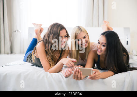 Ritratto di un felice tre amiche utilizza lo smartphone a casa Foto Stock