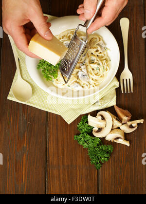Lo Chef grattugiare il formaggio parmigiano reggiano su pasta carbonara, vista dall'alto Foto Stock