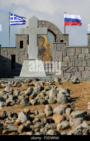 Vista ravvicinata del memorial Russian-Kozak circondato da una pietra-parete realizzata con le bandiere sventolano.Cape Punta. Villaggio Pesperago, Limnos Foto Stock