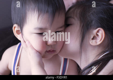 Piccola ragazza baciare fratellino sulla guancia Foto Stock