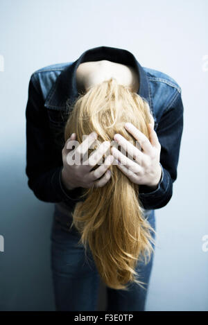 Donna sporgersi in avanti tenendo la testa Foto Stock