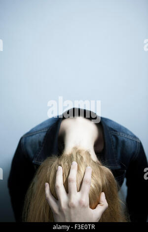 Donna sporgersi in avanti tenendo la testa Foto Stock
