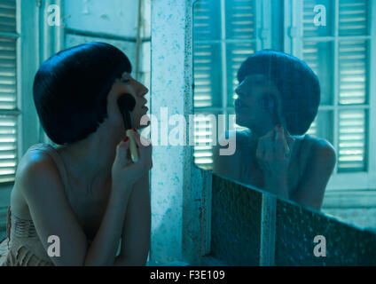 Donna che guarda in uno specchio, applicando arrossire Foto Stock