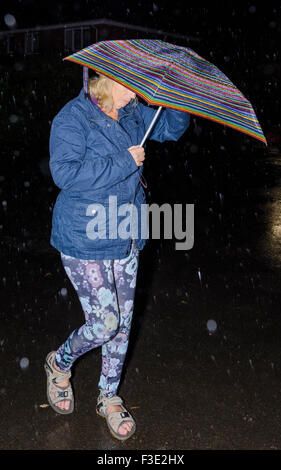 Donna anziana camminando sotto la pioggia durante la notte con ombrello. Foto Stock