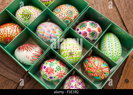 Dipinto a mano colorate uova di Pasqua nella casella verde su rustiche tavole di legno Foto Stock