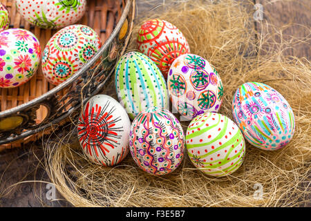 Dipinto a mano colorate uova di Pasqua nel nido su rustiche tavole di legno Foto Stock