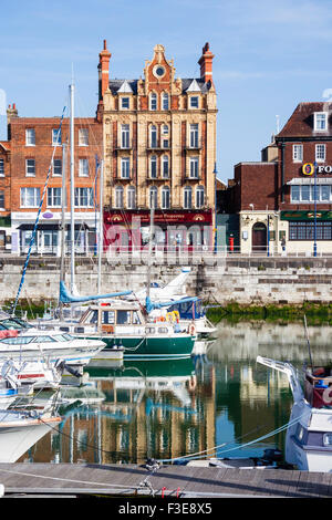 Inghilterra, Ramsgate. Il lungomare di cinque piani di edificio Georgiano, una volta che il "Royal Sailor's resto". Primo piano, piccole barche nel porto interno marina. Foto Stock