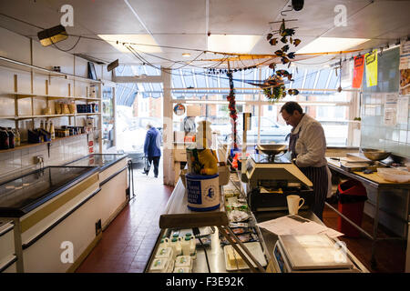 Interno del tipico inglese wet-pesce pesce mercanti shop. Vista lungo contatore a finestra anteriore display, lavoratori shop dietro il vetro banco espositore. Foto Stock