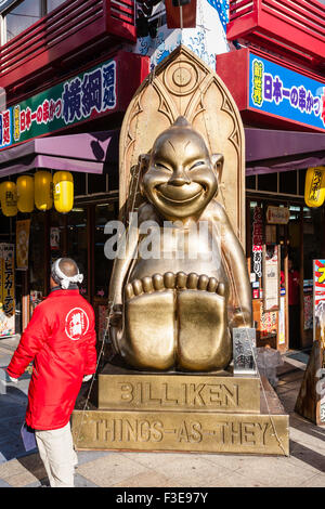 Osaka, Shinsekai. La famosa statua Billiken al di fuori del negozio sulla strada principale, un popolare buona fortuna icona dell'area. "Le cose come sono". Foto Stock