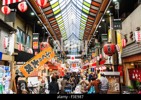 "Kuromon Ichiba', noto come Osaka cucina dell'interno di un lungo porticato coperto di negozi e bancarelle che vendono cibo, ma famoso per i suoi piatti di pesce. Occupato. Foto Stock