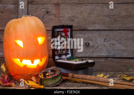 Zucca di Halloween di testa con la pesca con la mosca affronta su assi di legno sfondo Foto Stock