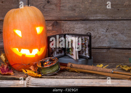 Zucca di Halloween di testa con la pesca con la mosca affronta su assi di legno sfondo Foto Stock