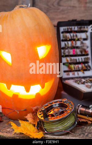 Zucca di Halloween di testa con la pesca con la mosca affronta su assi di legno sfondo Foto Stock