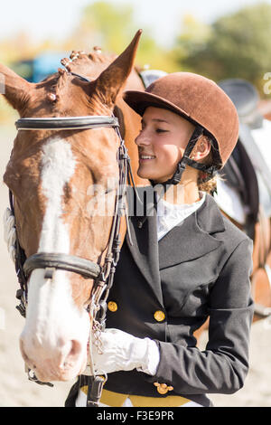 Giovane pilota sorridente ragazza con il suo cavallo Foto Stock