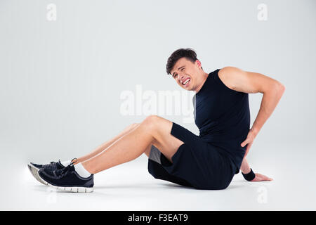 Ritratto di un uomo fitness avente dolore alla schiena isolato su uno sfondo bianco Foto Stock