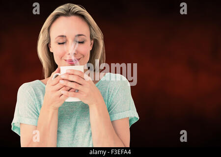 Immagine composita di allegro bionda tazza di contenimento di bevande calde Foto Stock