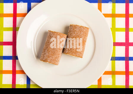 Due biscotti laminati e farcito con crema di latte in un colorato tovaglia con striping Foto Stock