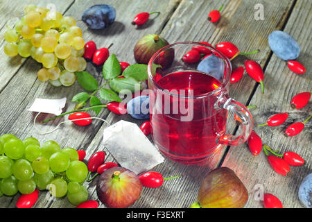 La rosa canina tea e frutti autunnali, su una tavola di legno tabe Foto Stock