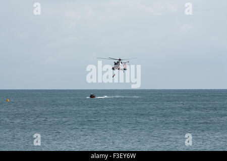 H.M Coastguard salvataggio elicottero abbassamento winchman a RNLI linshore scialuppa di salvataggio, lavorando insieme per l'esercizio al largo dell'isola di wight Coast, regno unito Foto Stock