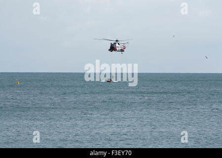 H.M Coastguard salvataggio elicottero abbassamento winchman a RNLI linshore scialuppa di salvataggio, lavorando insieme per l'esercizio al largo dell'isola di wight Coast, regno unito Foto Stock