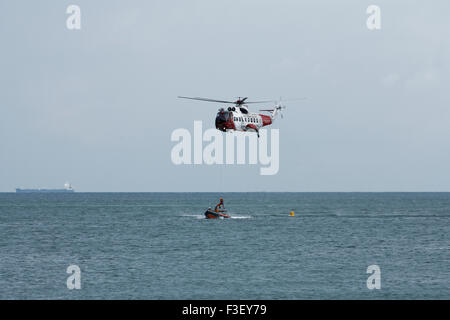 H.M Coastguard salvataggio elicottero abbassamento winchman a RNLI linshore scialuppa di salvataggio, lavorando insieme per l'esercizio al largo dell'isola di wight Coast, regno unito Foto Stock