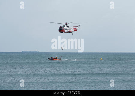 H.M Coastguard salvataggio elicottero abbassamento winchman a RNLI linshore scialuppa di salvataggio, lavorando insieme per l'esercizio al largo dell'isola di wight Coast, regno unito Foto Stock