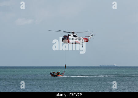 H.M Coastguard salvataggio elicottero abbassamento winchman a RNLI linshore scialuppa di salvataggio, lavorando insieme per l'esercizio al largo dell'isola di wight Coast, regno unito Foto Stock