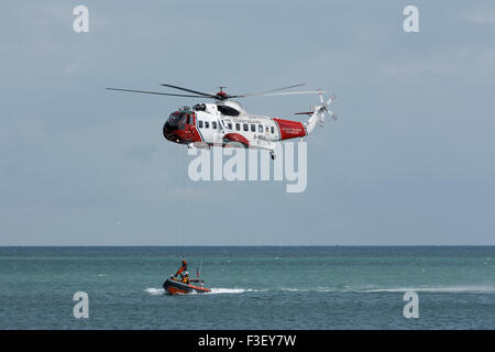 H.M Coastguard salvataggio elicottero abbassamento winchman a RNLI linshore scialuppa di salvataggio, lavorando insieme per l'esercizio al largo dell'isola di wight Coast, regno unito Foto Stock