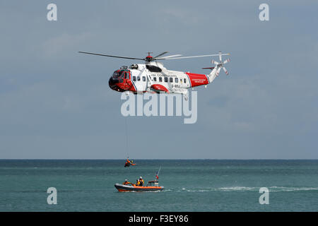 H.M Coastguard ricerca e salvataggio elicottero abbassamento verricello uomo a. Scialuppa di salvataggio costiera RNLI al largo dell'isola di wight Coast uk Foto Stock