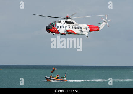 H.M Coastguard ricerca e salvataggio elicottero abbassamento verricello uomo a. Scialuppa di salvataggio costiera RNLI al largo dell'isola di wight Coast uk Foto Stock