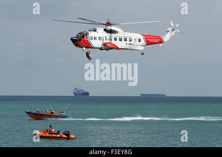 H.M Coastguard ricerca e salvataggio elicottero abbassamento verricello uomo a. Scialuppa di salvataggio costiera RNLI al largo dell'isola di wight Coast uk Foto Stock