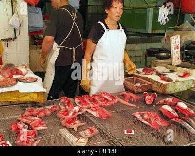 Pescivendolo cinese sul lavoro Preparazione del pesce per la vendita in un mercato di Hong Kong Foto Stock