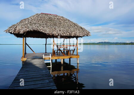 Capanna Palapa sopra l'acqua con palm con tetto in paglia tetto in una calma laguna Mar dei Caraibi, America centrale e di Panama Foto Stock
