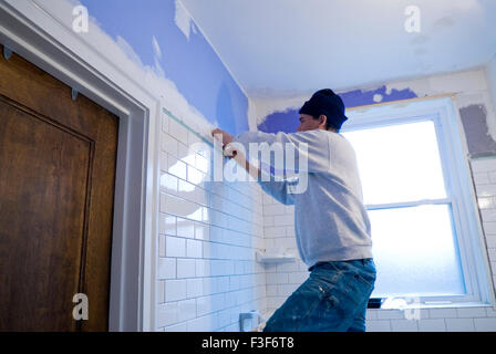 Uomo messicano tiling un muro di una stanza da bagno con piastrelle di metropolitana. Foto Stock