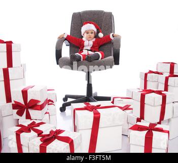 Baby boy in Santa Claus costume seduto sulla sedia da ufficio Foto Stock