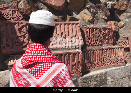 Ragazzo musulmano guardare ornamentazione islamica del Corano iscrizione scolpita Qutab Minar complesso di arenaria rossa Indo arte musulmana Delhi Foto Stock