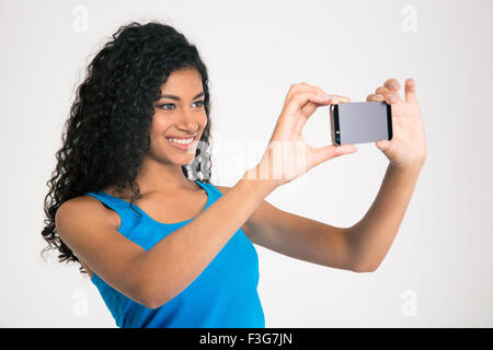 Ritratto di un sorridente afro american donna fare selfie foto sullo smartphone isolato su uno sfondo bianco Foto Stock