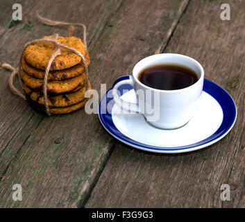 Ancora in vita una tazza di caffè e un collegamento di fiocchi d'avena i biscotti su una vecchia tabella Foto Stock