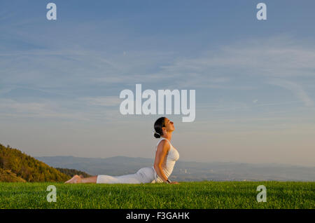Giovane donna pratica di Hatha Yoga outdoor, che mostra la posa bhujangasana, cobra pongono Foto Stock
